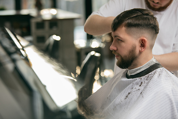 Image showing Close up master barber, stylist does the hairstyle to guy, young