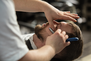 Image showing Close up hands of master barber, stylist does the hairstyle to guy, young man. Professional occupation, male beauty concept