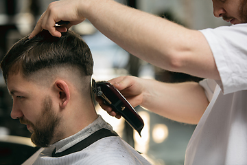 Image showing Close up master barber, stylist does the hairstyle to guy, young man. Professional occupation, male beauty concept