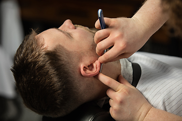 Image showing Close up hands of master barber, stylist does the hairstyle to guy, young man. Professional occupation, male beauty concept