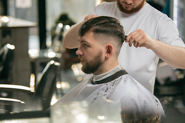 Image showing Close up master barber, stylist does the hairstyle to guy, young