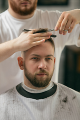 Image showing Close up master barber, stylist does the hairstyle to guy, young man. Professional occupation, male beauty concept