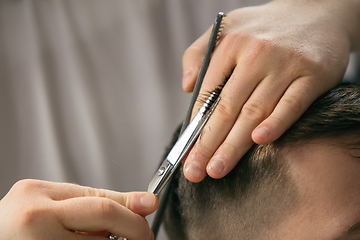 Image showing Close up hands of master barber, stylist does the hairstyle to guy, young man. Professional occupation, male beauty concept