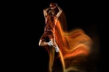 Image showing Young arabian basketball player of team in action, motion isolated on black background in mixed light. Concept of sport, movement, energy and dynamic.