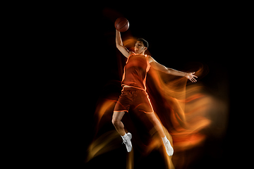 Image showing Young arabian basketball player of team in action, motion isolated on black background in mixed light. Concept of sport, movement, energy and dynamic.