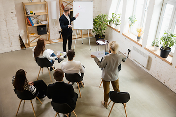 Image showing Male speaker giving presentation in hall at workshop. Audience or conference hall. High angle of unrecognized participants.