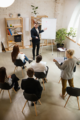 Image showing Male speaker giving presentation in hall at workshop. Audience or conference hall. High angle of unrecognized participants.