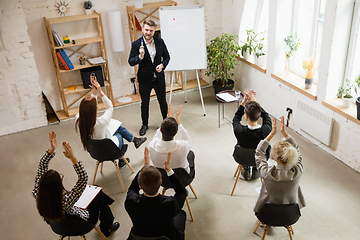 Image showing Male speaker giving presentation in hall at workshop. Audience or conference hall. High angle of unrecognized participants.