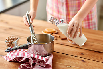 Image showing hands with whisk and milk cooking eggnog