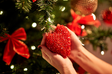 Image showing hands decorating christmas tree with red heart