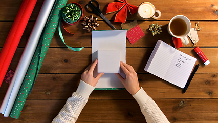 Image showing hands wrapping christmas gift into paper at home