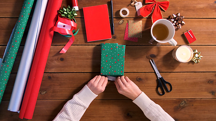 Image showing hands wrapping christmas gift into paper at home