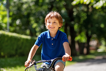 Image showing happy little boy riding bicycle at summer park