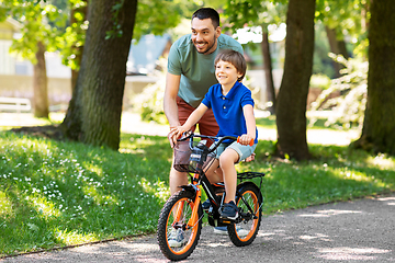 Image showing father teaching little son to ride bicycle at park