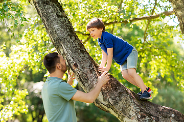 Image showing happy father with son climbing tree in summer park