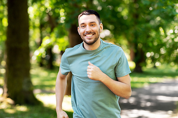 Image showing happy young man running at summer park