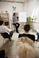 Image showing Female speaker giving presentation in hall at workshop. Audience or conference hall. Rear rview of unrecognized participants.