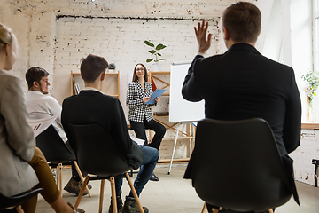 Image showing Female speaker giving presentation in hall at workshop. Audience or conference hall. Rear rview of unrecognized participants.