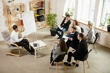 Image showing Male speaker giving presentation in hall at workshop. Audience or conference hall. High angle view of unrecognized participants.