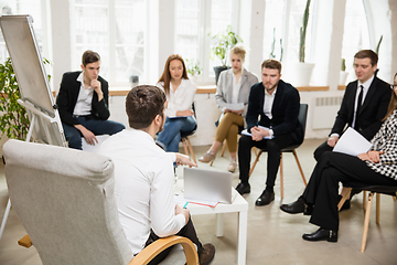 Image showing Male speaker giving presentation in hall at workshop. Audience or conference hall. Front view of attented listening participants.