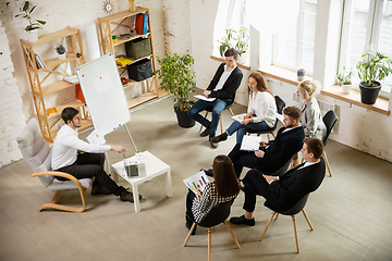 Image showing Male speaker giving presentation in hall at workshop. Audience or conference hall. High angle view of unrecognized participants.