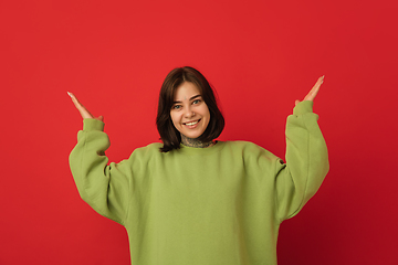 Image showing Caucasian woman\'s portrait isolated on red studio background with copyspace