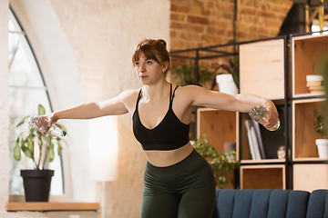 Image showing Young woman exercising fitness, aerobic, yoga at home, sporty lifestyle. Getting active during lockdown, quarantine. Home gym.