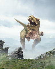 Image showing Dinosaur huge higth walking through the jungle, foggy mountains