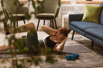 Image showing Young woman exercising fitness, aerobic, yoga at home, sporty lifestyle. Getting active during lockdown, quarantine. Home gym.