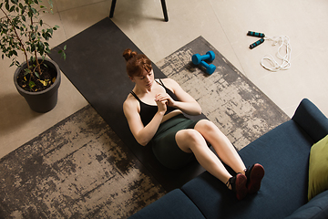 Image showing Young woman exercising fitness, aerobic, yoga at home, sporty lifestyle. Getting active during lockdown, quarantine. Home gym.