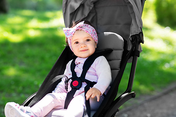 Image showing happy baby girl sitting in stroller at summer park