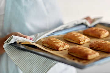 Image showing woman holding baking tray with pies at kitchen