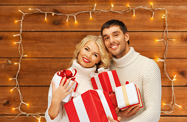 Image showing happy couple in sweaters with christmas gifts