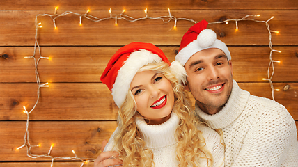 Image showing happy couple in sweaters and santa hats