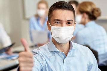 Image showing businessman in mask showing thumbs up at office