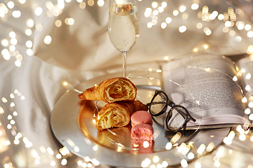 Image showing champagne, croissants, book and glasses in bed