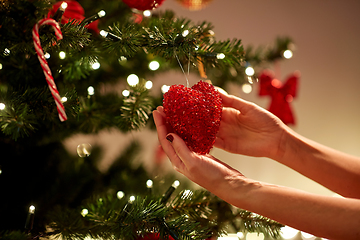 Image showing hands decorating christmas tree with red heart