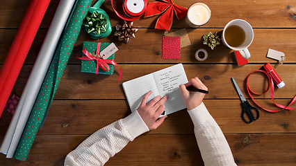 Image showing hands writing to do list in notebook on christmas