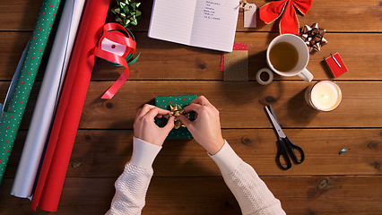 Image showing hands packing christmas gift and attaching bow