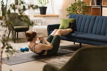 Image showing Young woman exercising fitness, aerobic, yoga at home, sporty lifestyle. Getting active during lockdown, quarantine. Home gym.