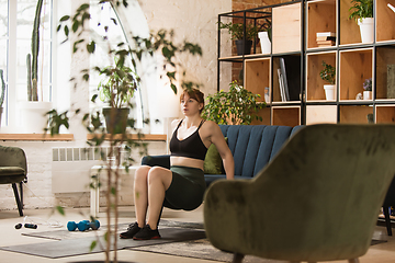 Image showing Young woman exercising fitness, aerobic, yoga at home, sporty lifestyle. Getting active during lockdown, quarantine. Home gym.