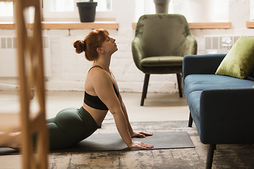 Image showing Young woman exercising fitness, aerobic, yoga at home, sporty lifestyle. Getting active during lockdown, quarantine. Home gym.