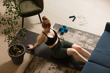 Image showing Young woman exercising fitness, aerobic, yoga at home, sporty lifestyle. Getting active during lockdown, quarantine. Home gym.