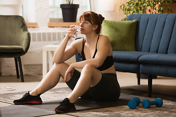 Image showing Young woman exercising fitness, aerobic, yoga at home, sporty lifestyle. Getting active during lockdown, quarantine. Home gym.