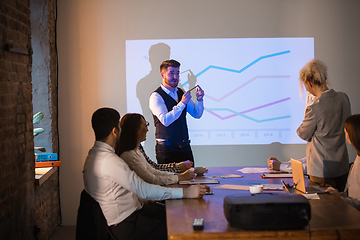 Image showing Male speaker giving presentation in hall at workshop. Audience or conference hall. Participants, co-workers listening at the table.