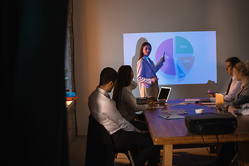 Image showing Female speaker giving presentation in hall at workshop. Audience or conference hall. Participants, co-workers listening at the table.