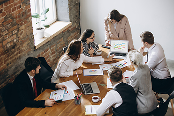 Image showing Female speaker giving presentation in hall at workshop. Audience or conference hall. Participants, co-workers listening at the table.