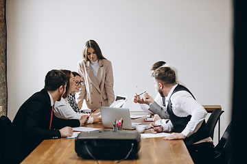 Image showing Female speaker giving presentation in hall at workshop. Audience or conference hall. Participants, co-workers listening at the table.