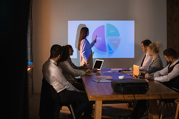 Image showing Female speaker giving presentation in hall at workshop. Audience or conference hall. Participants, co-workers listening at the table.