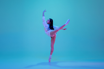 Image showing Young and graceful ballet dancer isolated on blue studio background in neon light. Art, motion, action, flexibility, inspiration concept.